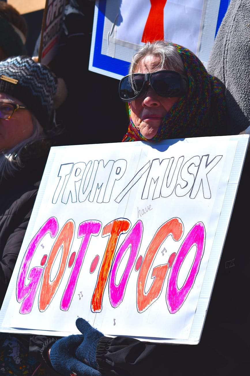 protester holding sign against trump and musk